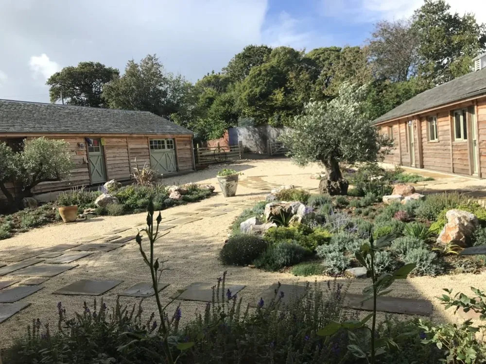 The courtyard at Namaste Barn in Ideford, timber stable blocks around a gravel garden