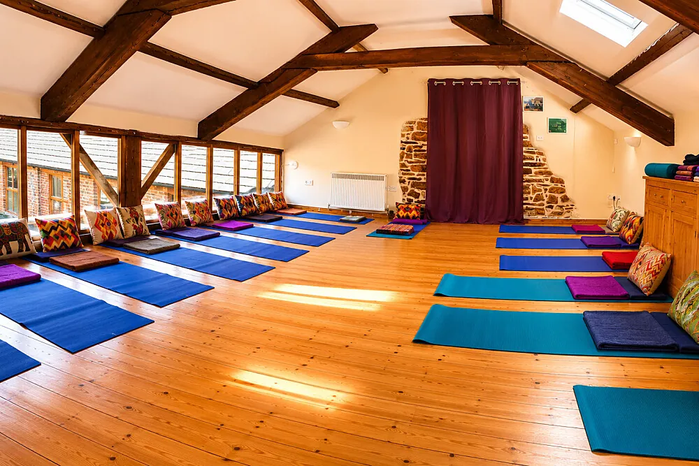 The beamed yoga studio at Newhouse Farm Cottages near Witheridge, with mats laid out on a pine floor